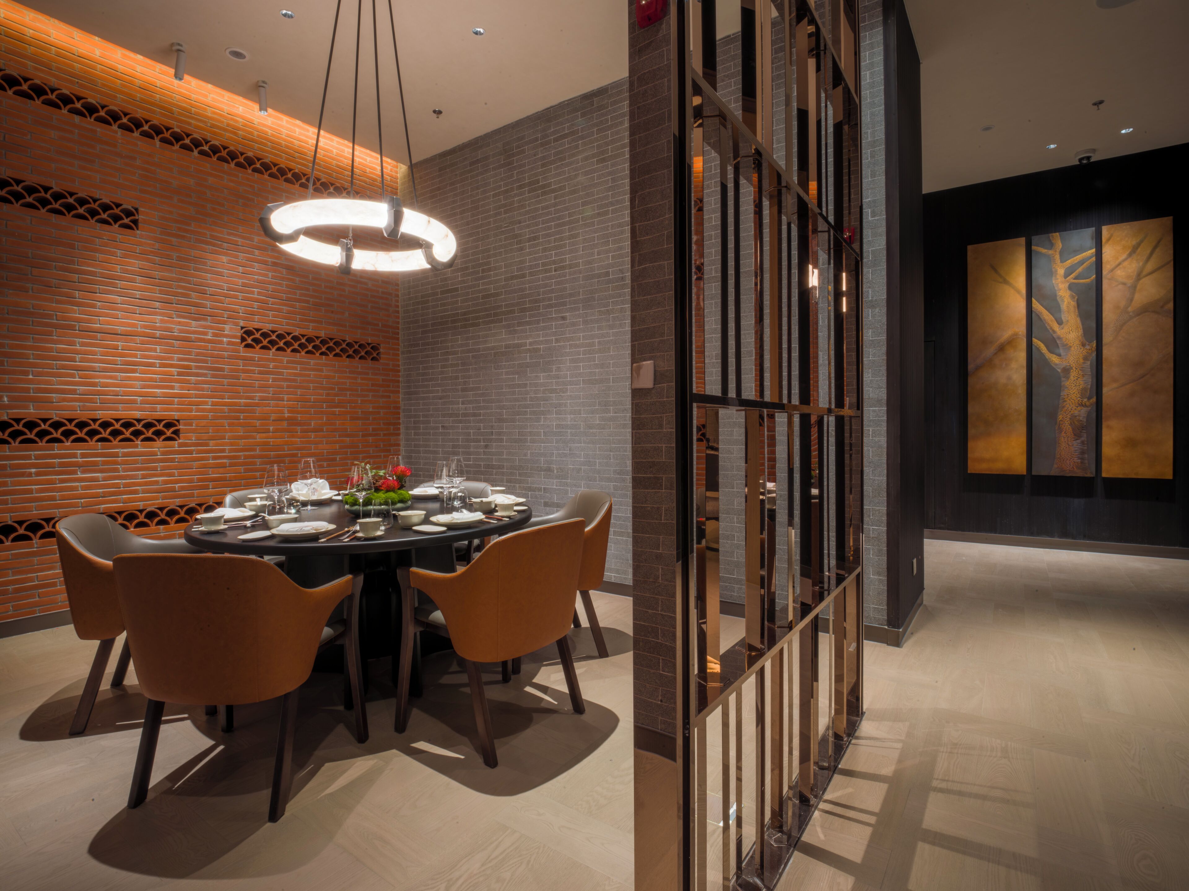 A modern dining area with a brick wall, a round table set for four, and a large window with a view of trees.