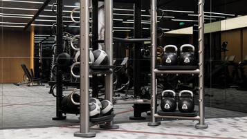 Un gimnasio con equipo de levantamiento de pesas, cintas de correr y un espejo grande.
