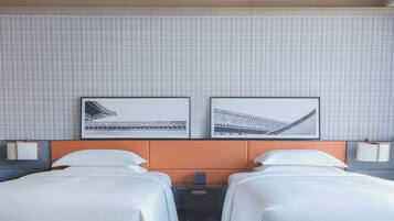 A hotel room with two beds, a tiled wall, and two framed pictures.