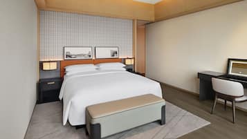 A modern hotel room with a bed, bedside tables, a desk, and a chair.