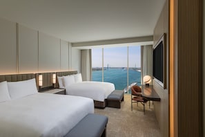 A hotel room with two beds, a desk, a chair, and a large window with a view of a body of water and a bridge. - JW Marriott Detroit Water Square (Detroit)
