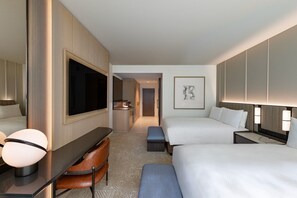 A hotel room with a bed, a desk, a chair, a TV, and a bathroom.