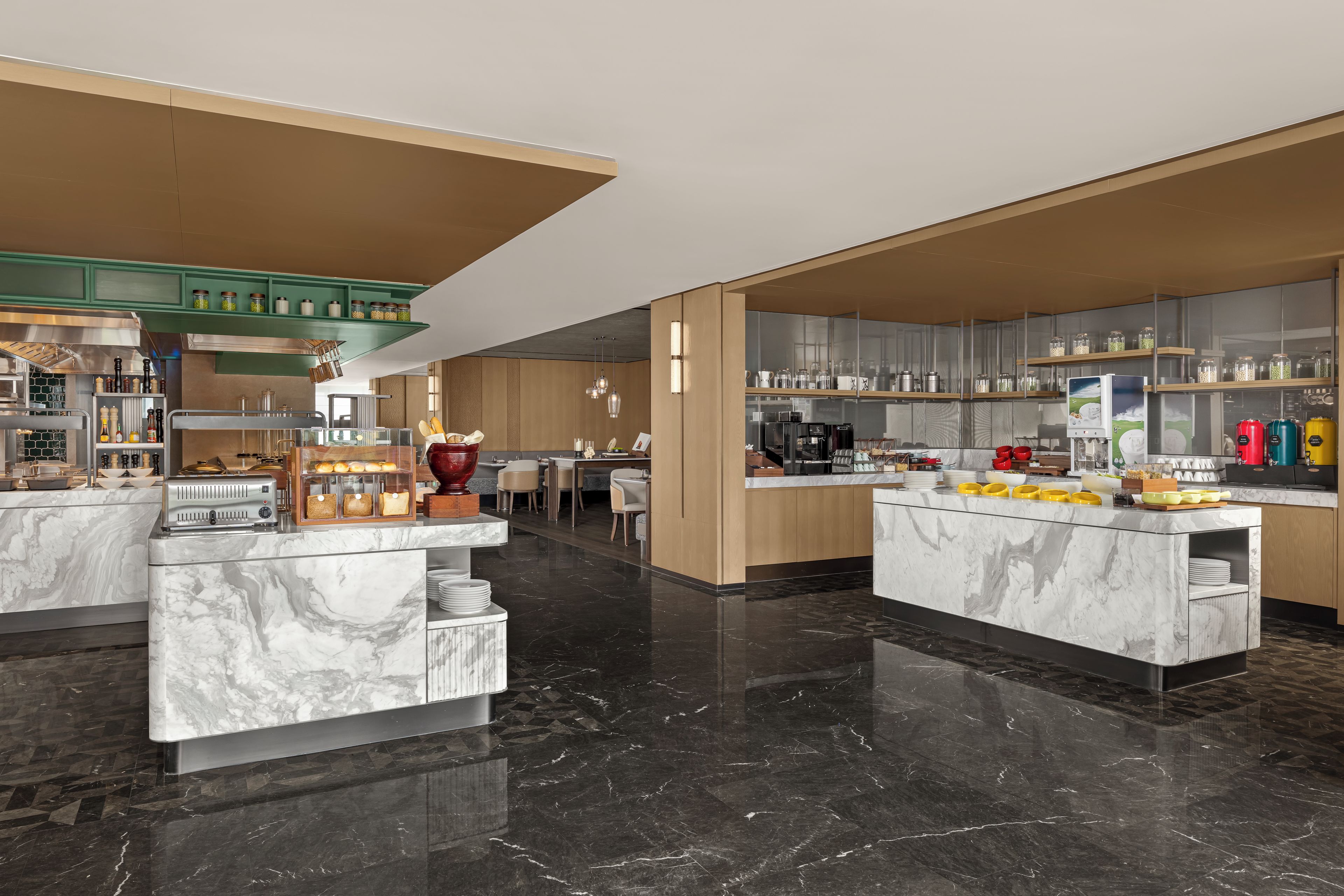 A modern kitchen with marble countertops, stainless steel appliances, and a variety of food items displayed.