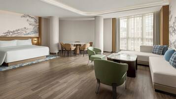 A hotel room with a bed, a dining table with chairs, a sofa, and a coffee table.