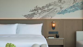 Una habitación de hotel moderna con una cama grande, una mesita de noche con lámpara y un mural decorativo en la pared.