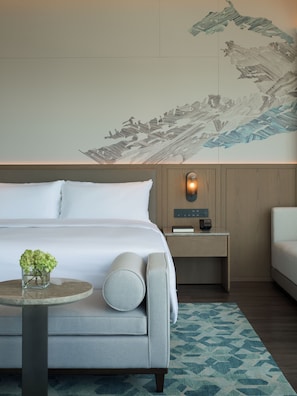 Una habitación de hotel moderna con una cama grande, una mesita de noche con lámpara y un mural decorativo en la pared.
