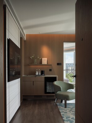 A modern kitchen with wooden cabinets, a built-in refrigerator, and a seating area with a chair and a table.