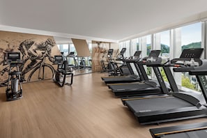Un gimnasio con cintas de correr, bicicletas estáticas y una máquina de remo.