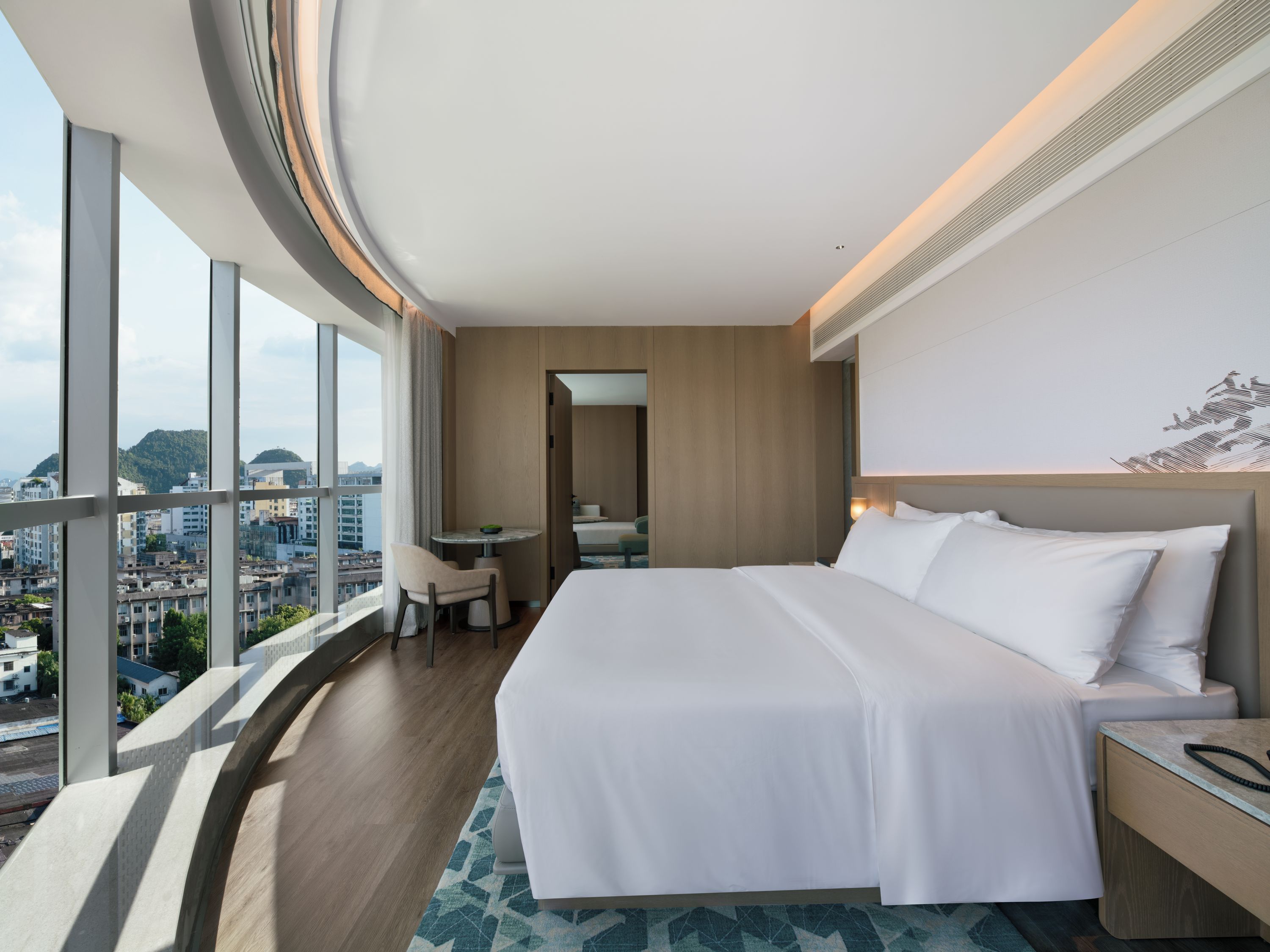 Una habitación de hotel con una cama grande, un escritorio y vistas a la ciudad.