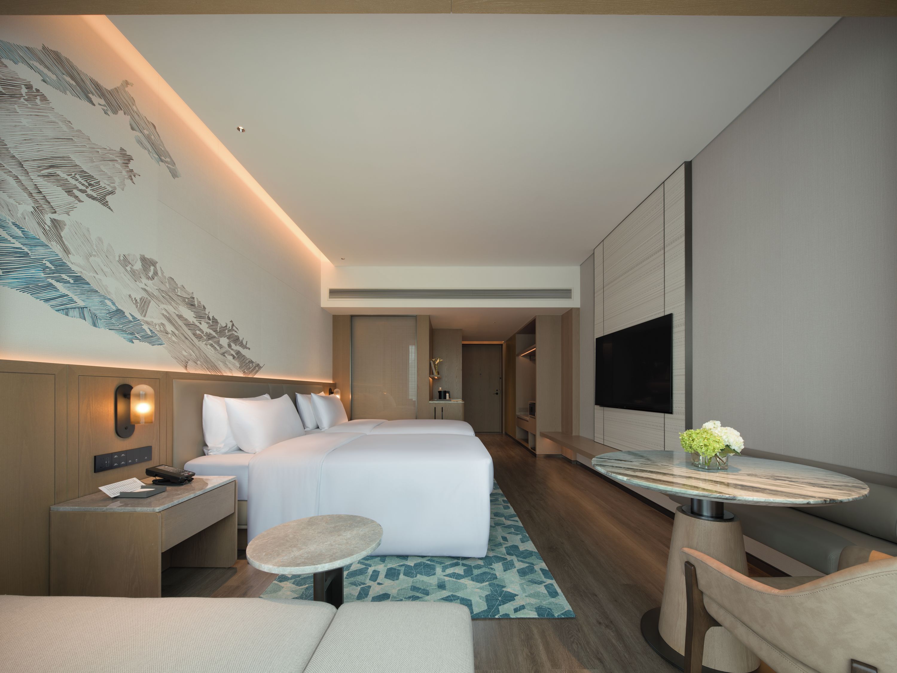 Une chambre d’hôtel moderne équipée d’un lit, d’une table de chevet, d’une lampe et d’un téléviseur à écran plat.