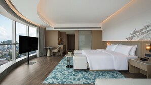A modern hotel room with a large bed, a flat-screen TV, a desk, and a view of the city. - Courtyard By Marriott Guilin Downtown (Guilin)