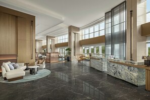 Eine geräumige Lobby mit einer Rezeption, einer Sitzecke und großen Fenstern mit Blick.