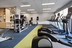 Un gimnasio con cintas de correr, elípticas y equipo de pesas.