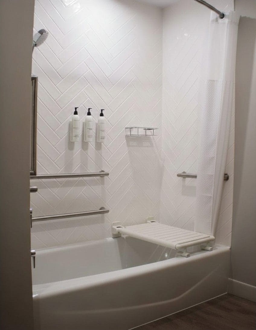 Een inloopdouche met een witte betegelde wand, een douchekop, een handdoekhouder en een plank met toiletartikelen.