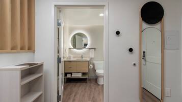 A modern bathroom with a wooden vanity, a round mirror, and a toilet.