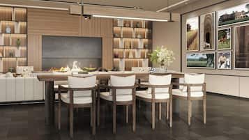 A modern dining area with a central fire feature, wooden panel walls, and a large flat-screen TV.