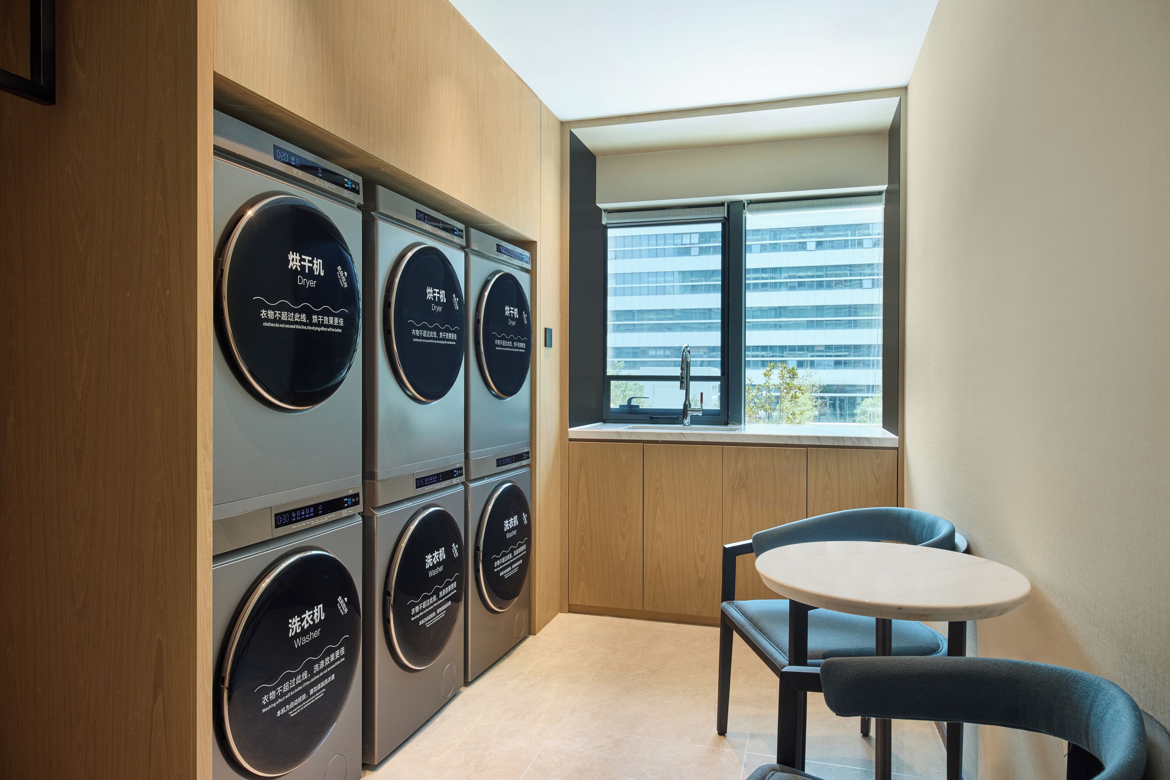 A laundry room with a washing machine, dryer, and a window with a view of a building.