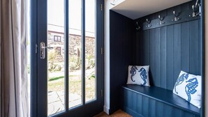 Ein Zimmer mit einer Bank, einer Tür mit Ausblick nach draußen und einer Wand mit Haken.
