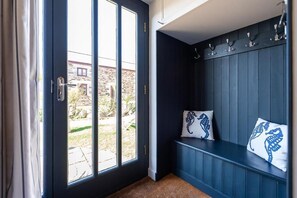 A room with a bench, a door with a view to the outside, and a wall with hooks. - 3 Bed in Mawgan Porth (oc-b584383) (Mawgan Porth)