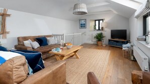 Ein modernes Wohnzimmer mit Sofa, Couchtisch und Fernseher.