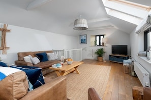 A modern living room with a sofa, coffee table, and a television. - 3 Bed in Mawgan Porth (oc-b584383) (Mawgan Porth)