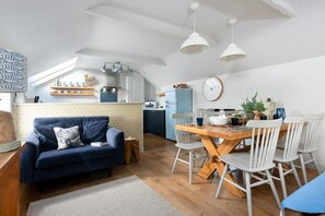 Un espace de vie compact comprenant un canapé, une table à manger et un coin cuisine.