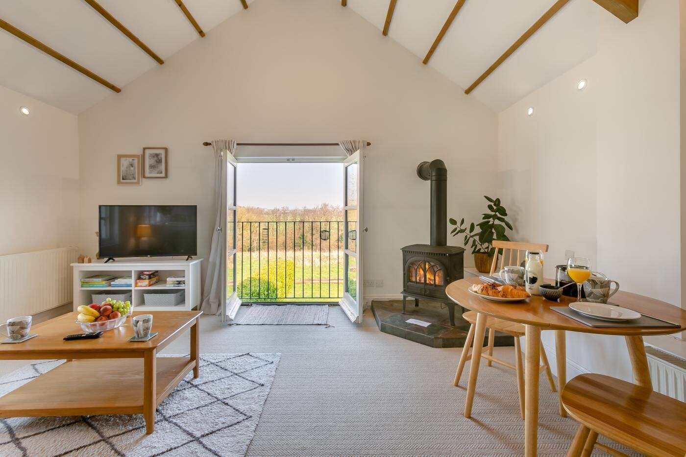 A cozy living room with a television, a dining table set for two, and a fireplace.
