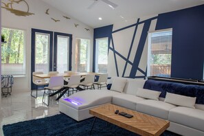 Ein modernes Wohnzimmer mit einer Eckcouch, einem Couchtisch und einem Essbereich mit Stühlen und einem Tisch.