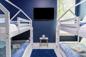 A room with bunk beds, a flat-screen TV mounted on the wall, and a small table with a lamp. - Hot Tub+Game Room+Pet-Friendly+Lake Access+FirePit (Mabank)