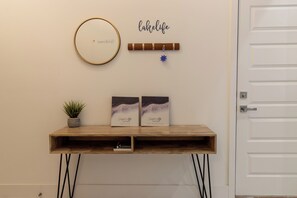 A wooden console table with two framed items, a small potted plant, and a wall-mounted decorative item with the word 'Calhielife'. - Hot Tub+Game Room+Pet-Friendly+Lake Access+FirePit (Mabank)