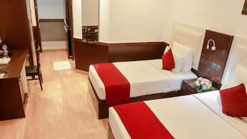 A hotel room with two beds, a desk, and a mirror.