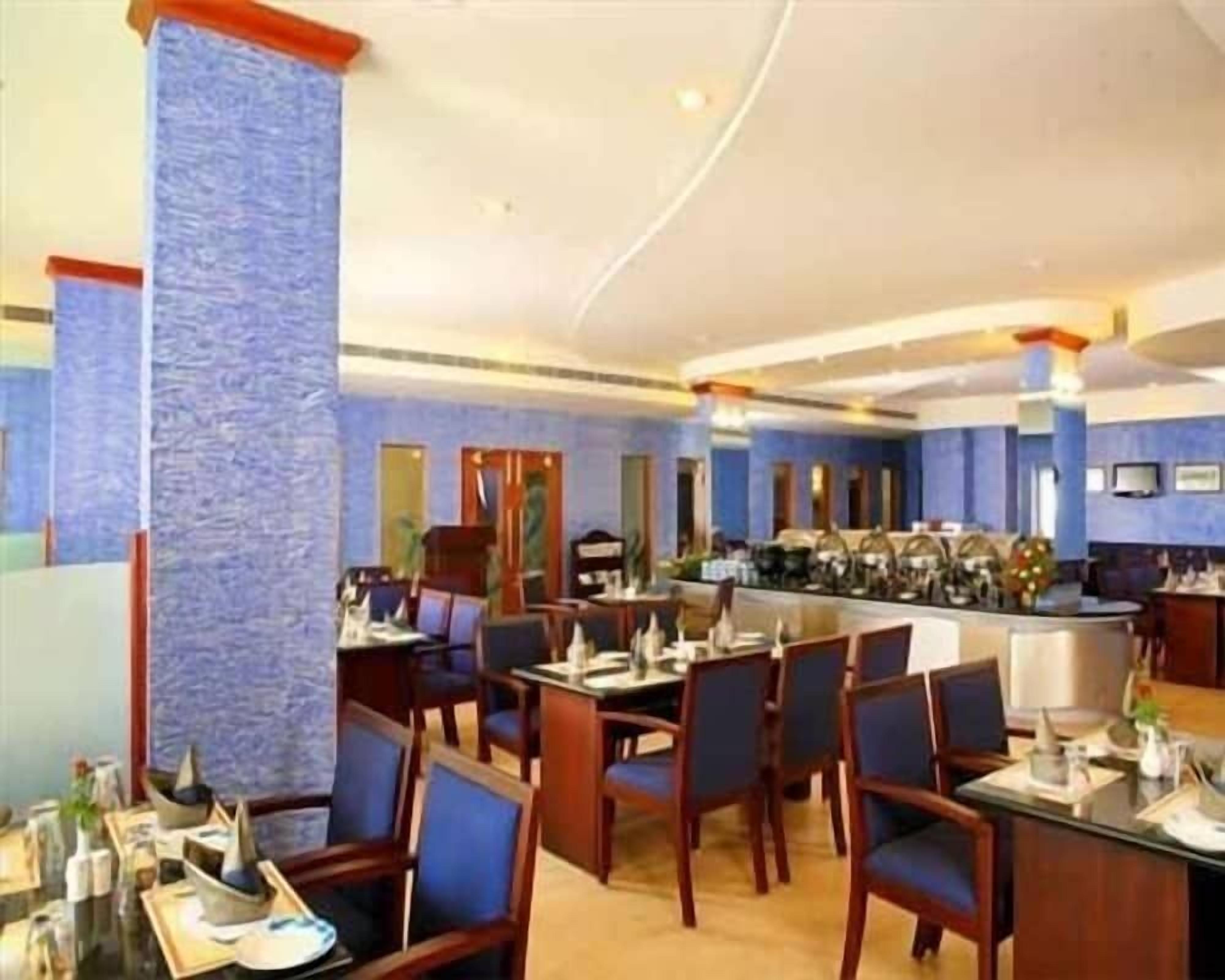 A hotel dining area with tables and chairs, a bar, and a large pillar.