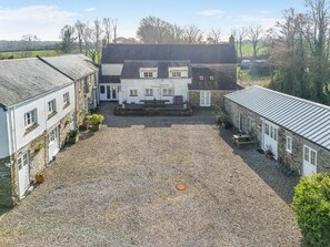A courtyard with a gravel ground, surrounded by buildings with stone walls and tiled roofs. - 1 Bed in Summercourt (oc-o36891) (Summercourt)
