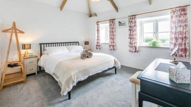 Een slaapkamer met een bed, nachtkastje, lamp en een houten ladder.