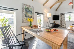 A dining area with a wooden table, chairs, a vase of flowers, and a plate of food. - 1 Bed in Summercourt (oc-o36891) (Summercourt)