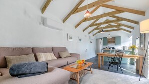 Een moderne woonkamer met een bank, een bijzettafeltje met fruit en een eethoek met een tafel en stoelen.