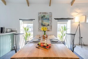 A dining area with a wooden table, chairs, a vase with flowers, and a painting on the wall. - 1 Bed in Summercourt (oc-o36891) (Summercourt)