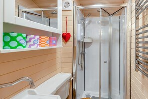 Ein Badezimmer mit Dusche, Waschbecken und einem Regal mit bunten Kisten.