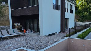 A modern building with a flat roof, a paved patio area with outdoor seating, and a staircase leading to an upper level. - Two Bedroom Villa with Swimming Pool (Jastrebarsko)