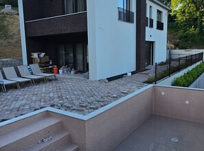 A modern building with a flat roof, a paved patio area with outdoor seating, and a staircase leading to an upper level. - Two Bedroom Villa with Swimming Pool (Jastrebarsko)