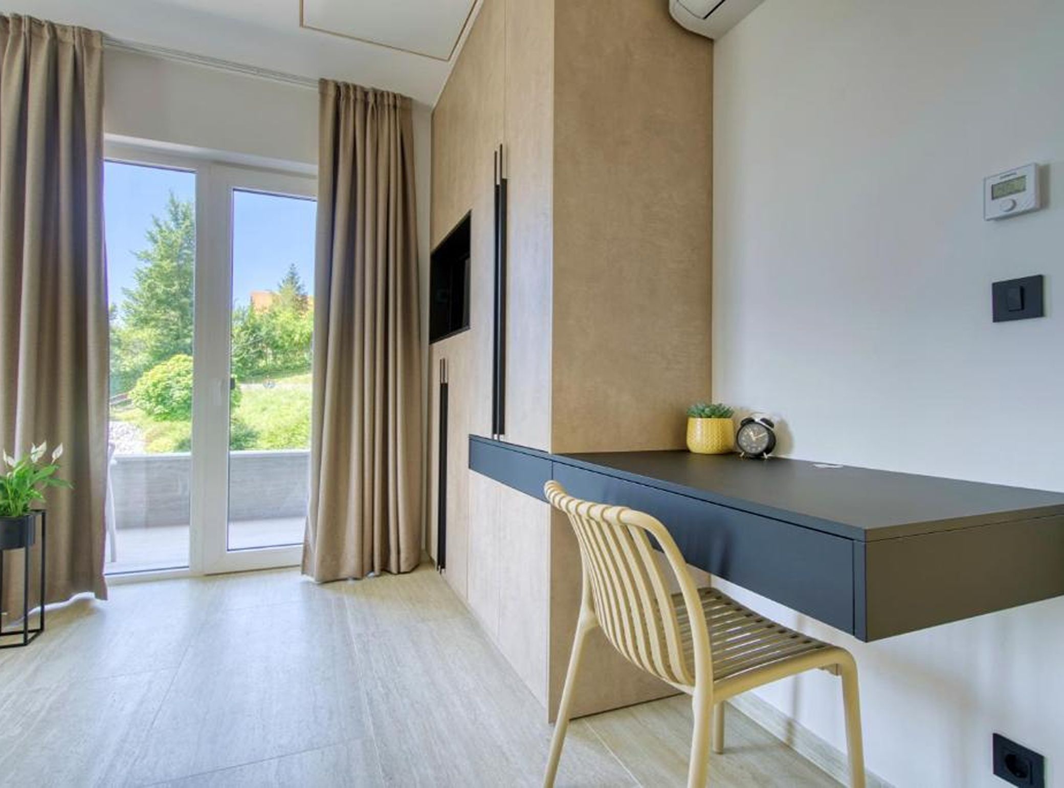 A modern room with a desk, chair, and a television.