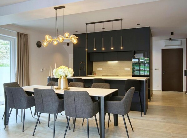 A modern kitchen with dark cabinetry, a central island, and pendant lighting.