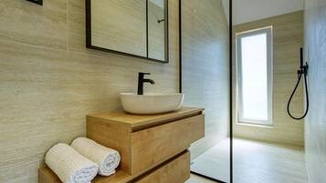A modern bathroom with a wooden vanity, a white sink, and a large mirror.
