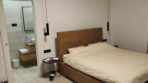 A hotel room with a bed, bedside table, and a small table with a lamp. - Two Bedroom Villa with Swimming Pool (Jastrebarsko)