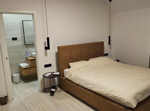 A hotel room with a bed, bedside table, and a small table with a lamp. - Two Bedroom Villa with Swimming Pool (Jastrebarsko)