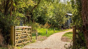 A gravel path leading through a wooded area with a wooden gate. - 1 Bed in West Yelland (oc-o45728) (Braunton)