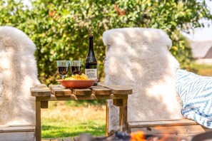 Mesa de madeira com arrumação para piquenique, incluindo uma garrafa de vinho, dois copos e uma tigela de batatas fritas.
