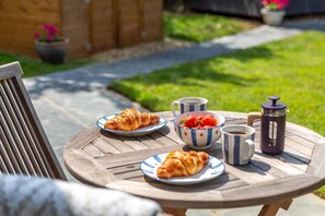 Ein runder Holztisch mit Speisen, einer Kaffeekanne und Tassen.