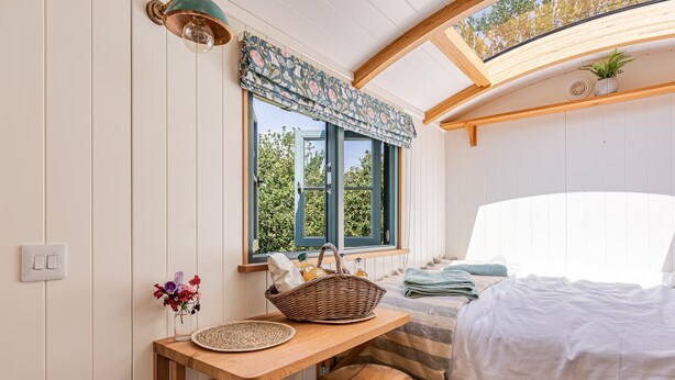 A cozy room with a bed, a window with a view, a table with a basket, and a stool. - 1 Bed in West Yelland (oc-o45728) (Braunton)