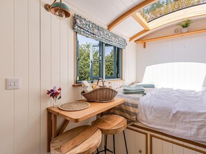 A cozy room with a bed, a window with a view, a table with a basket, and a stool. - 1 Bed in West Yelland (oc-o45728) (Braunton)
